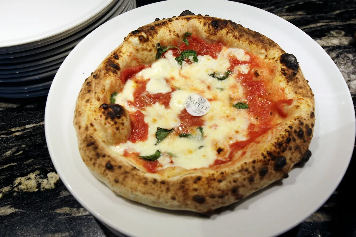 Man sieht eine Pizza Magaritha mit einem Sticker "Napule" in der Mitte.